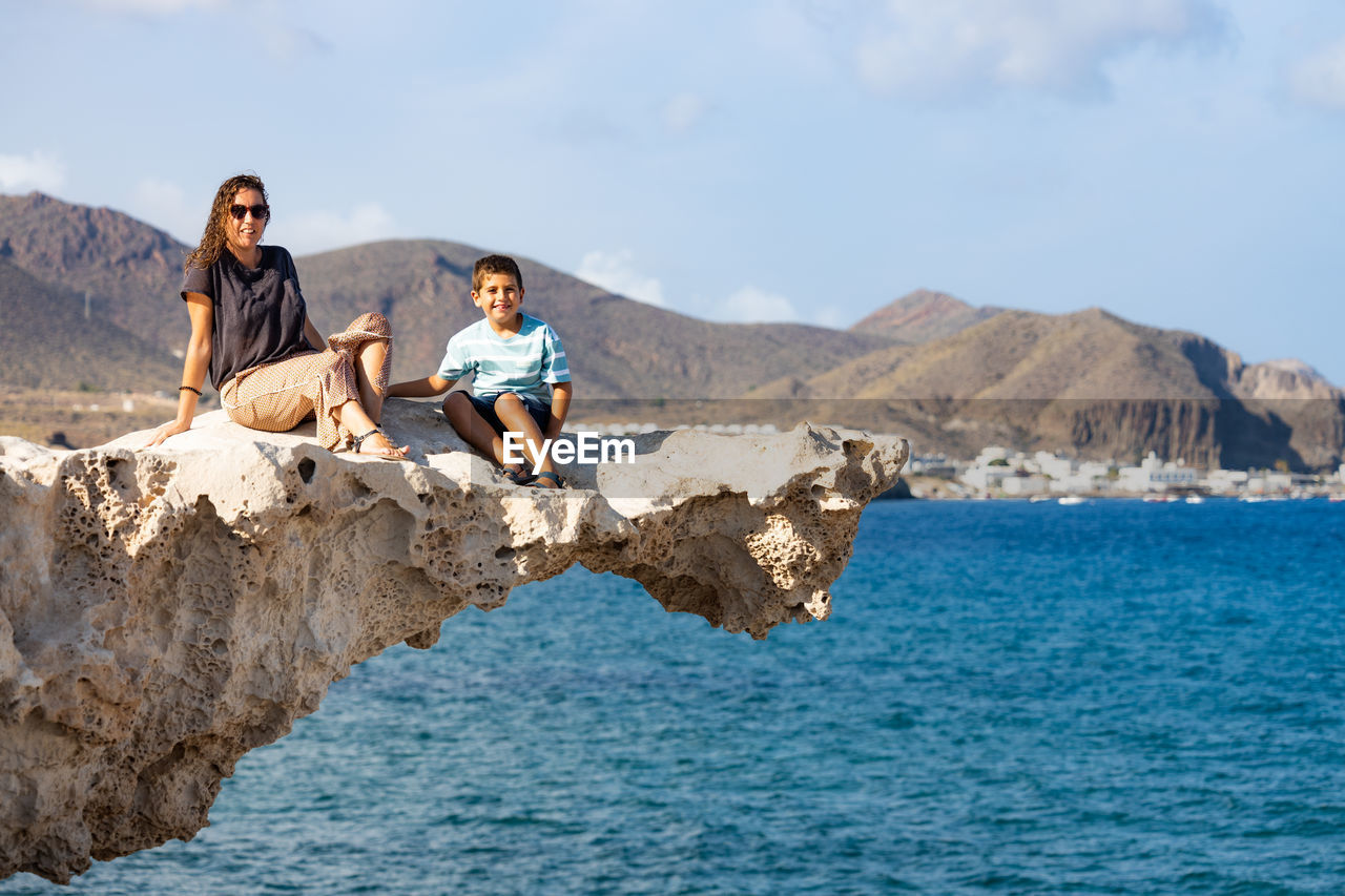 Woman and kid on a rock of playa del arco, almeria, spain