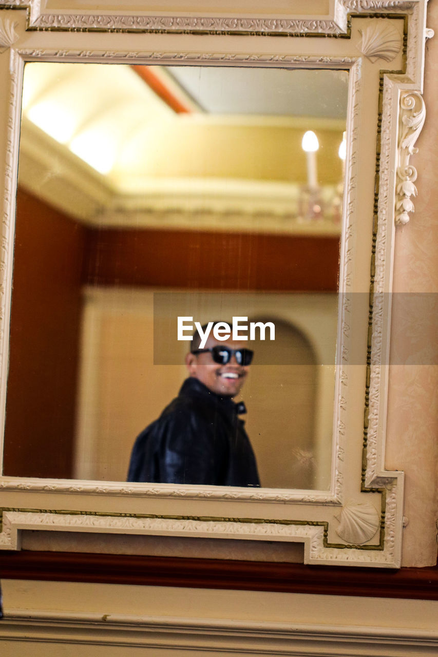 Man wearing sunglasses reflecting on mirror