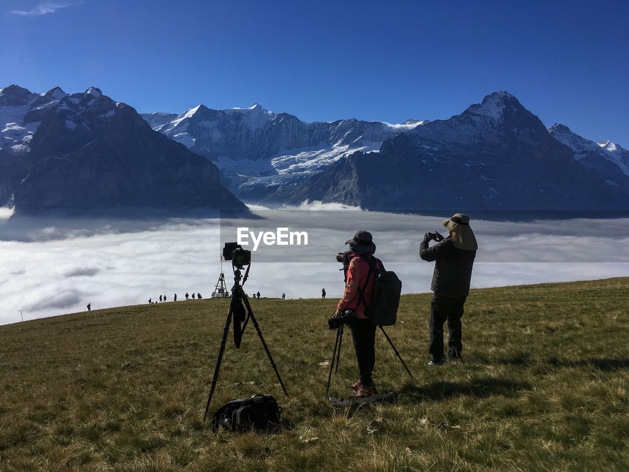 Man and woman photographing snowcapped mountains amidst cloudscape