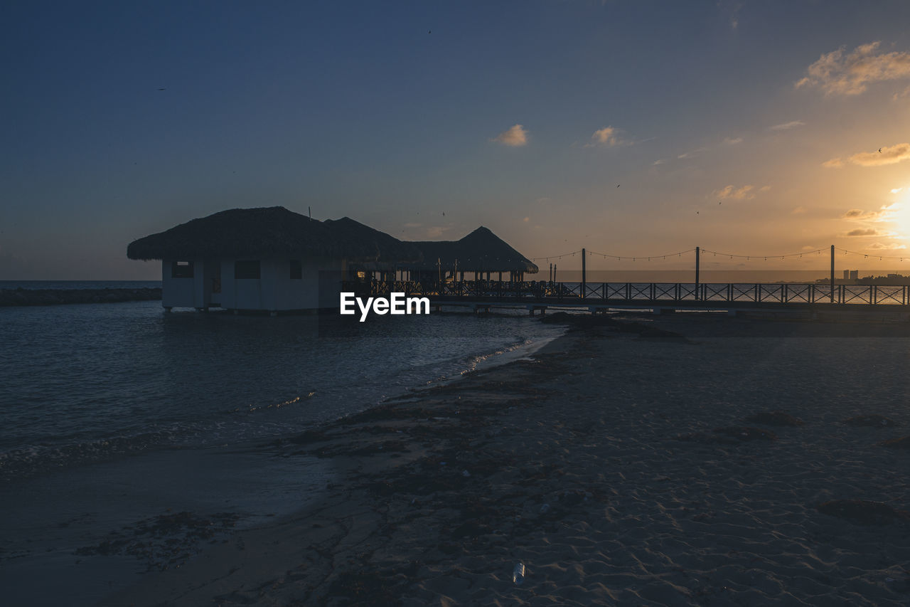 HOUSES BY SEA AGAINST SKY DURING SUNSET