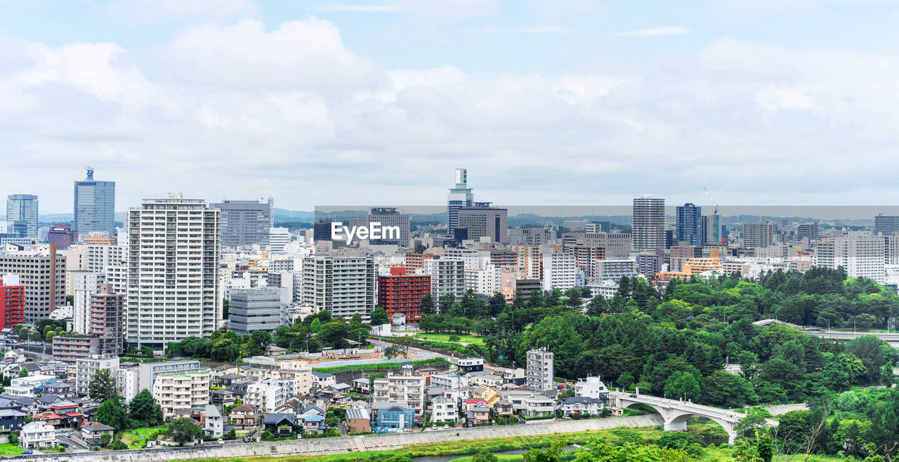 HIGH ANGLE VIEW OF BUILDINGS AND TREES AGAINST SKY