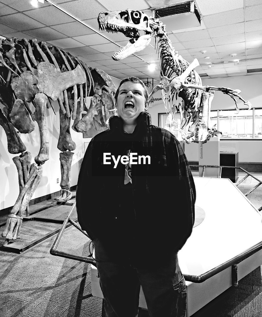 Boy making face while standing amidst animal skeletons