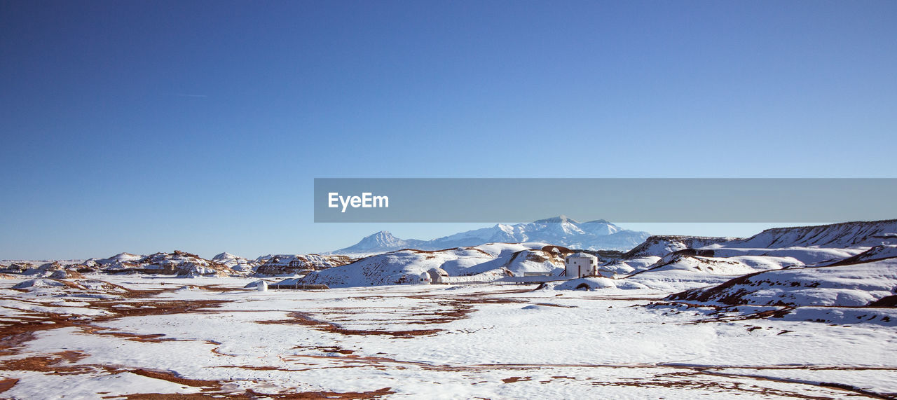 Scenic view of snowcapped mountains against clear blue sky