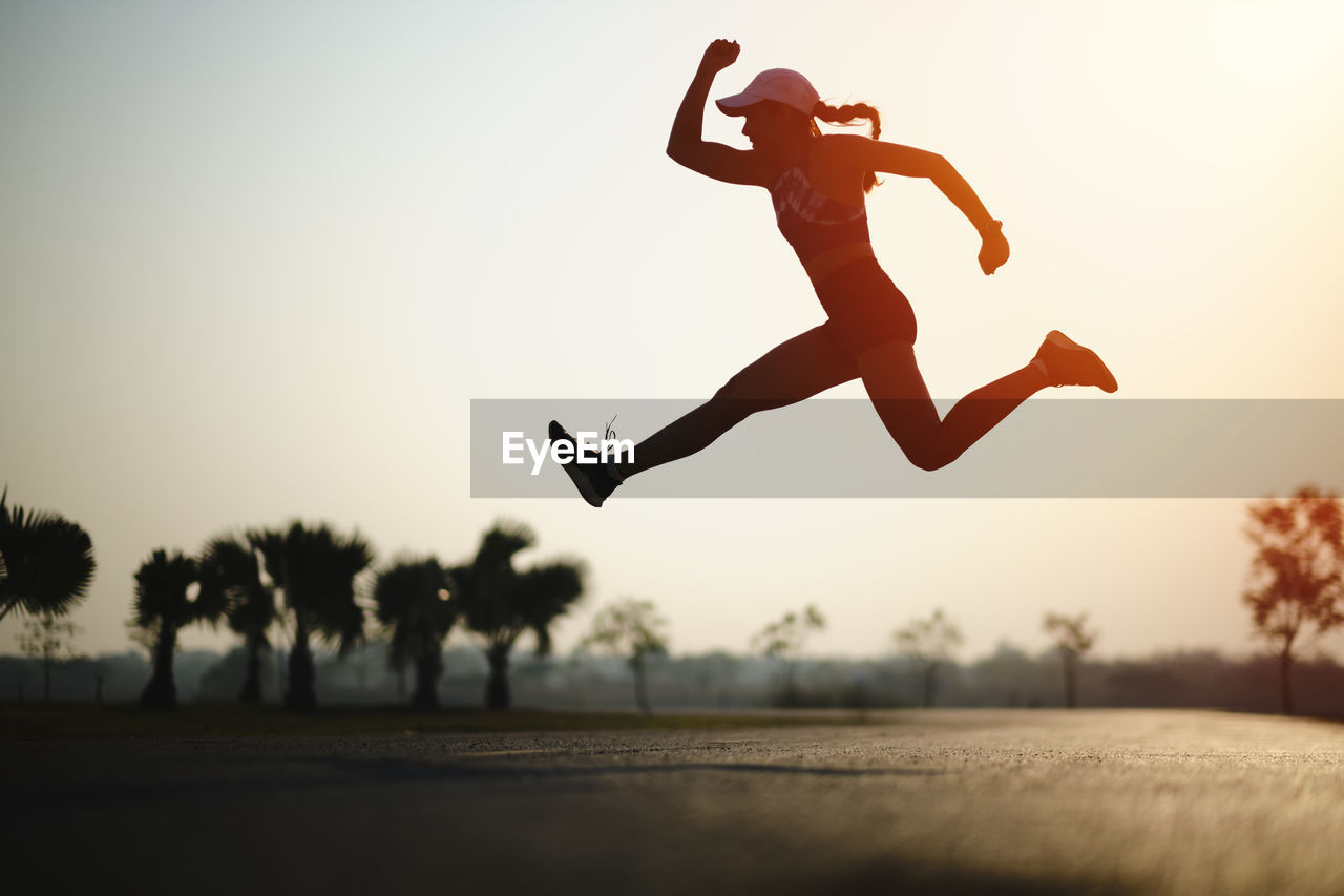 Full length of silhouette woman jumping against sky 