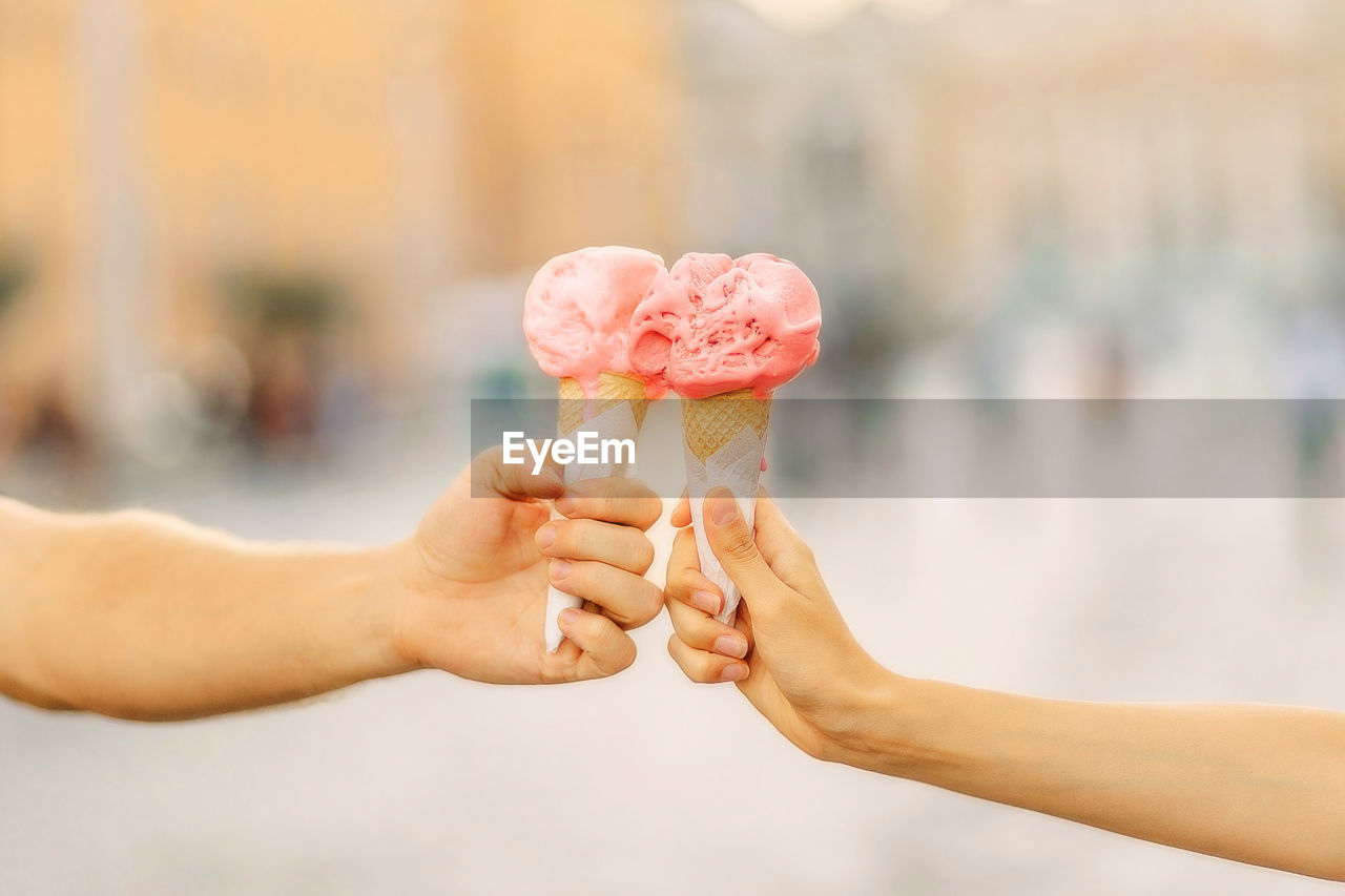 Men's and women's hands hold bright ice cream cone. hands holding ice cream cone. summertime. 