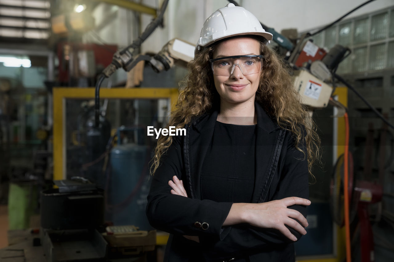 Portrait of smiling engineer wearing hard hat standing in factory