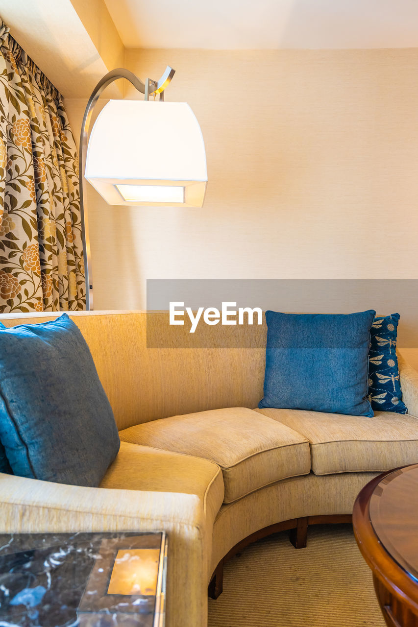 Close-up of illuminated lamp over sofa at hotel room