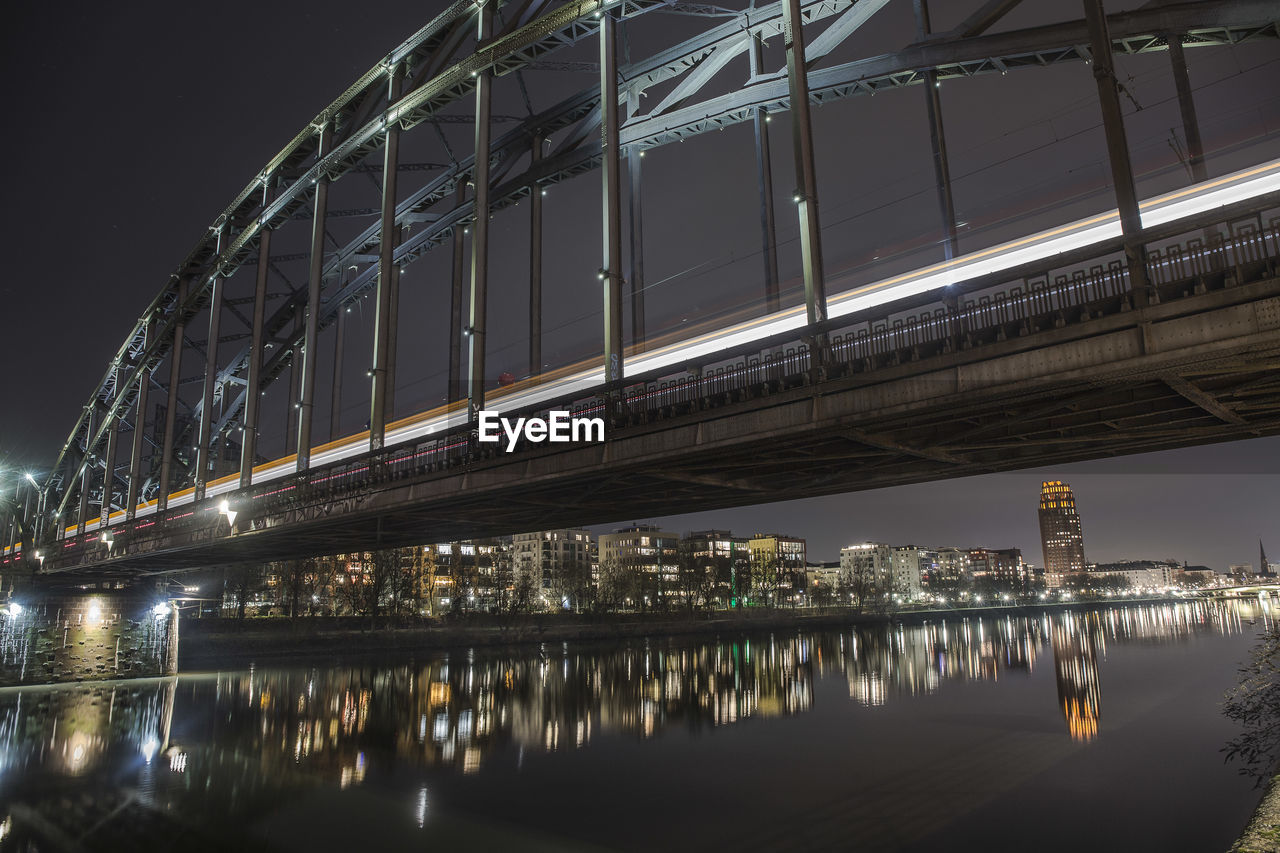 Illuminated bridge over river against sky at night