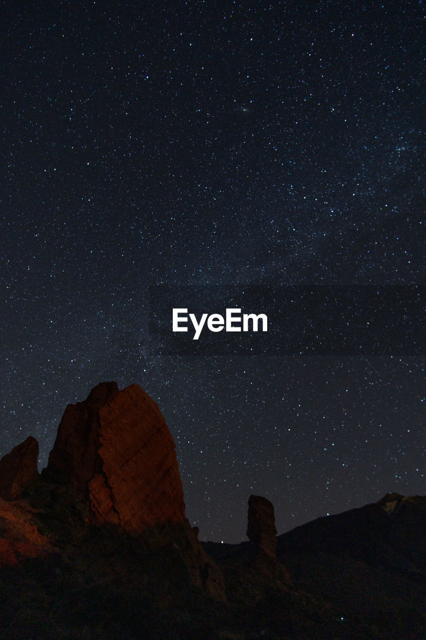 LOW ANGLE VIEW OF ROCK FORMATIONS AGAINST STAR FIELD