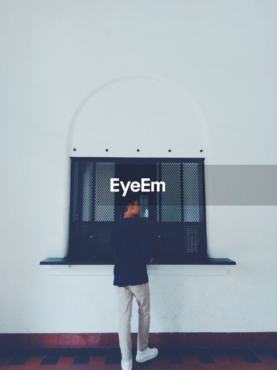 Rear view of young man standing against wall