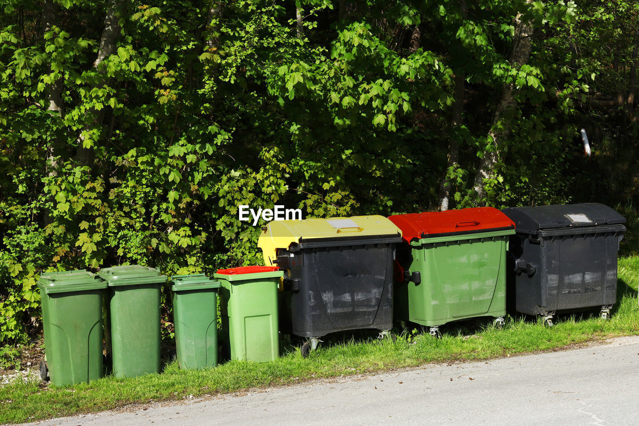 plant, waste container, tree, green, nature, day, no people, garbage bin, waste containment, transportation, growth, outdoors, transport, container, in a row, road, recycling, side by side, recycling bin, sunlight, street, environment, rural area