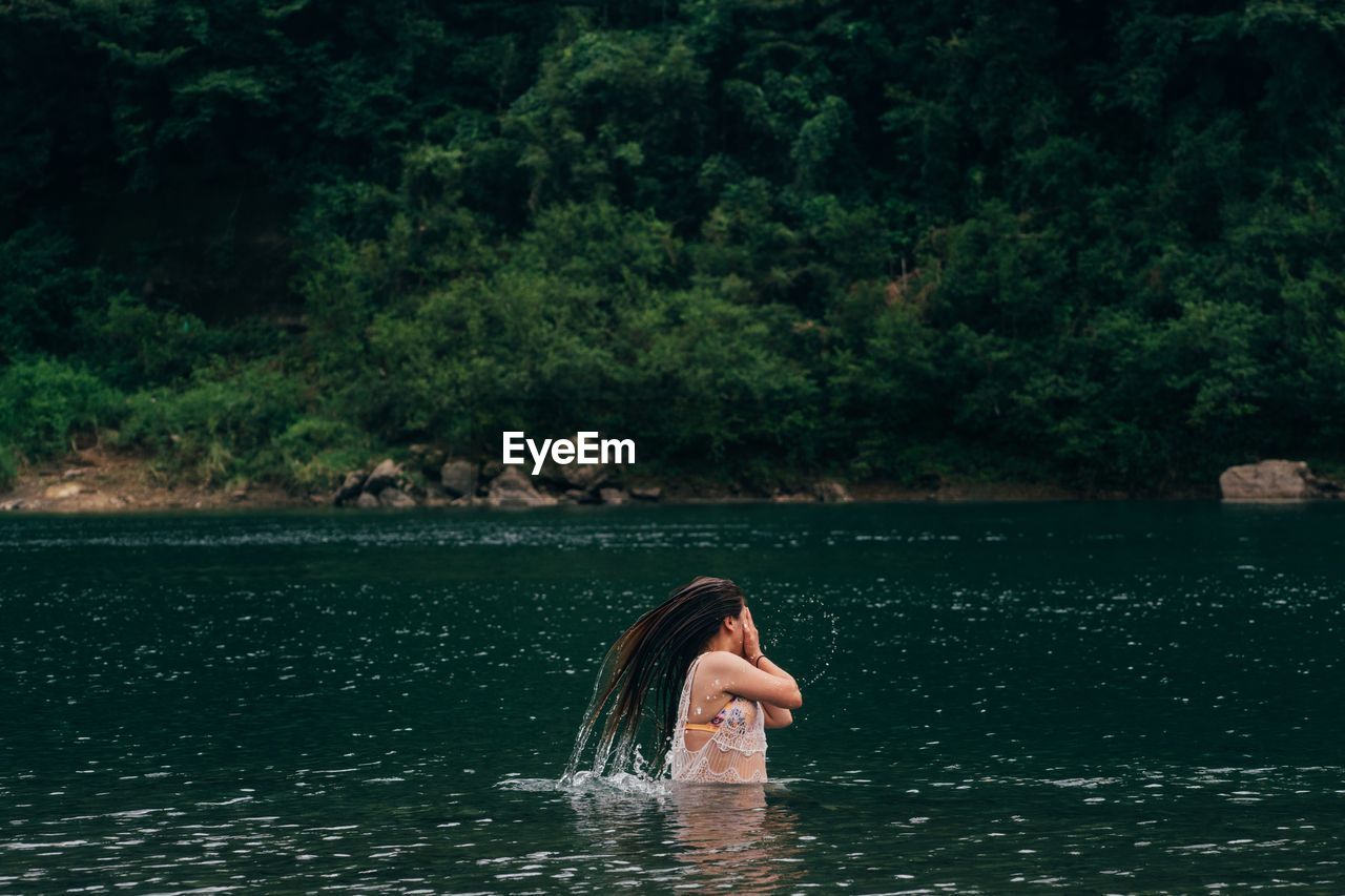 Woman tossing hair in lake 