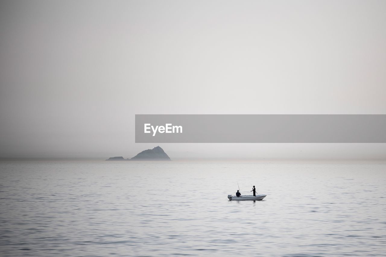 People sailing boat in sea against sky