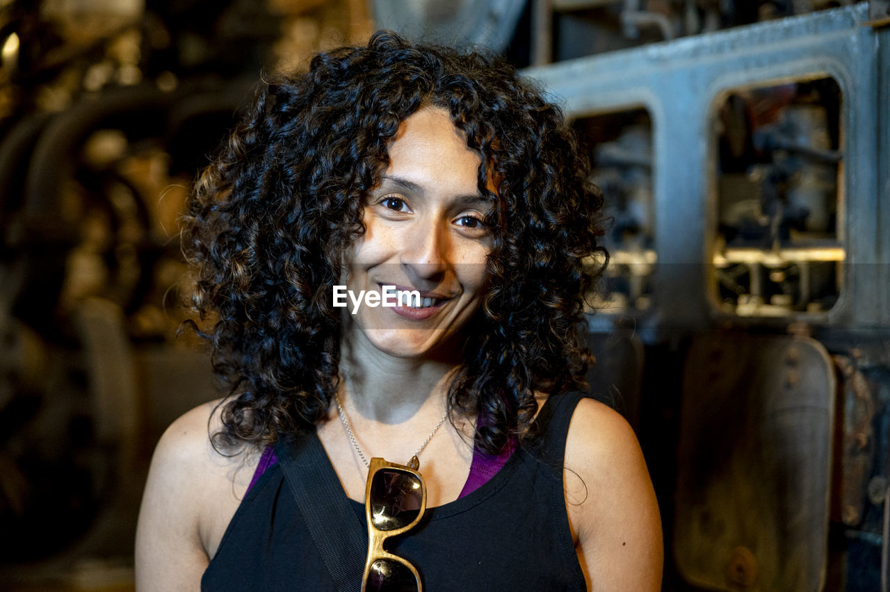 Portrait of a mixed race woman smiling while posing inside an abandoned factory.