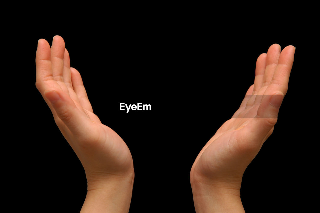 Cropped hands of woman gesturing against black background