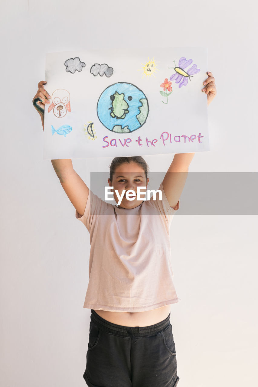 Smiling girl holding poster of earth planet at home