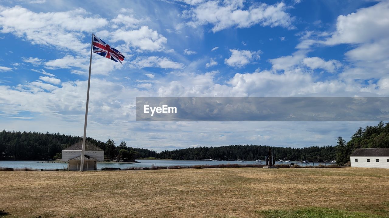 flag, sky, patriotism, cloud, nature, environment, architecture, wind, built structure, day, tree, no people, plant, land, landscape, building exterior, outdoors, grass, building, blue, travel destinations, scenics - nature, rural area