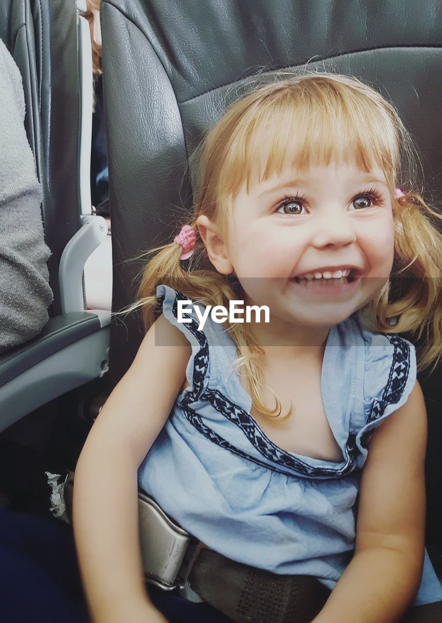 Happy girl with blond hair on vehicle seat