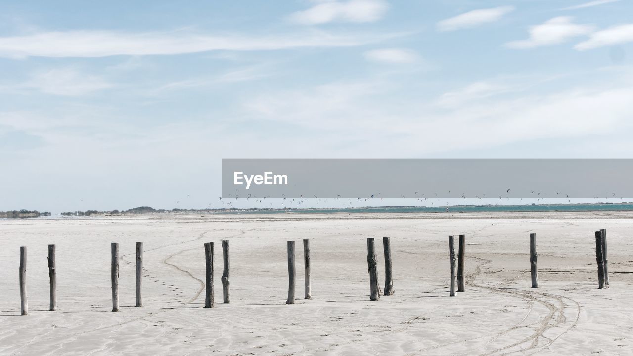 Wooden posts on beach against sky