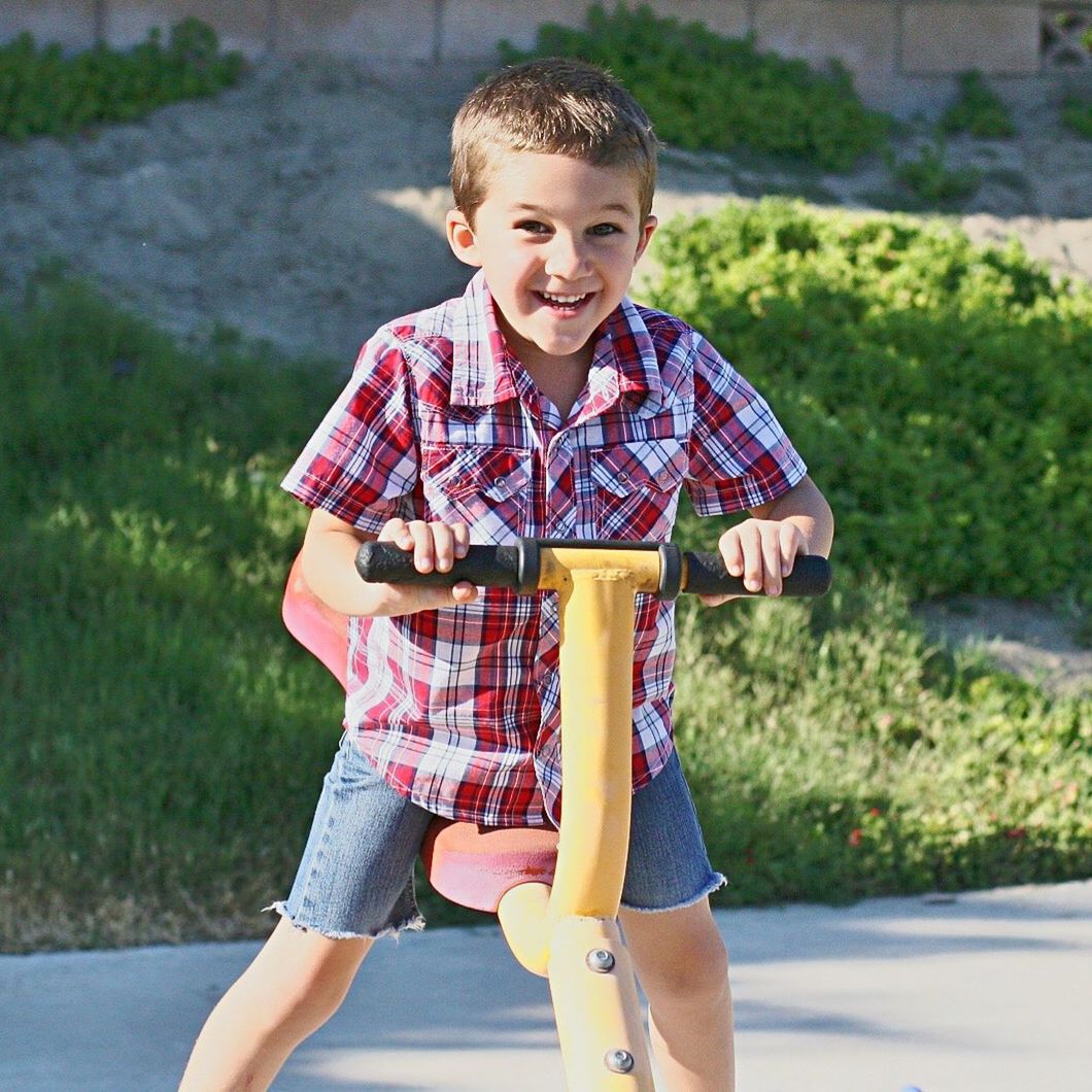 Portrait of smiling boy playing on seesaw at park