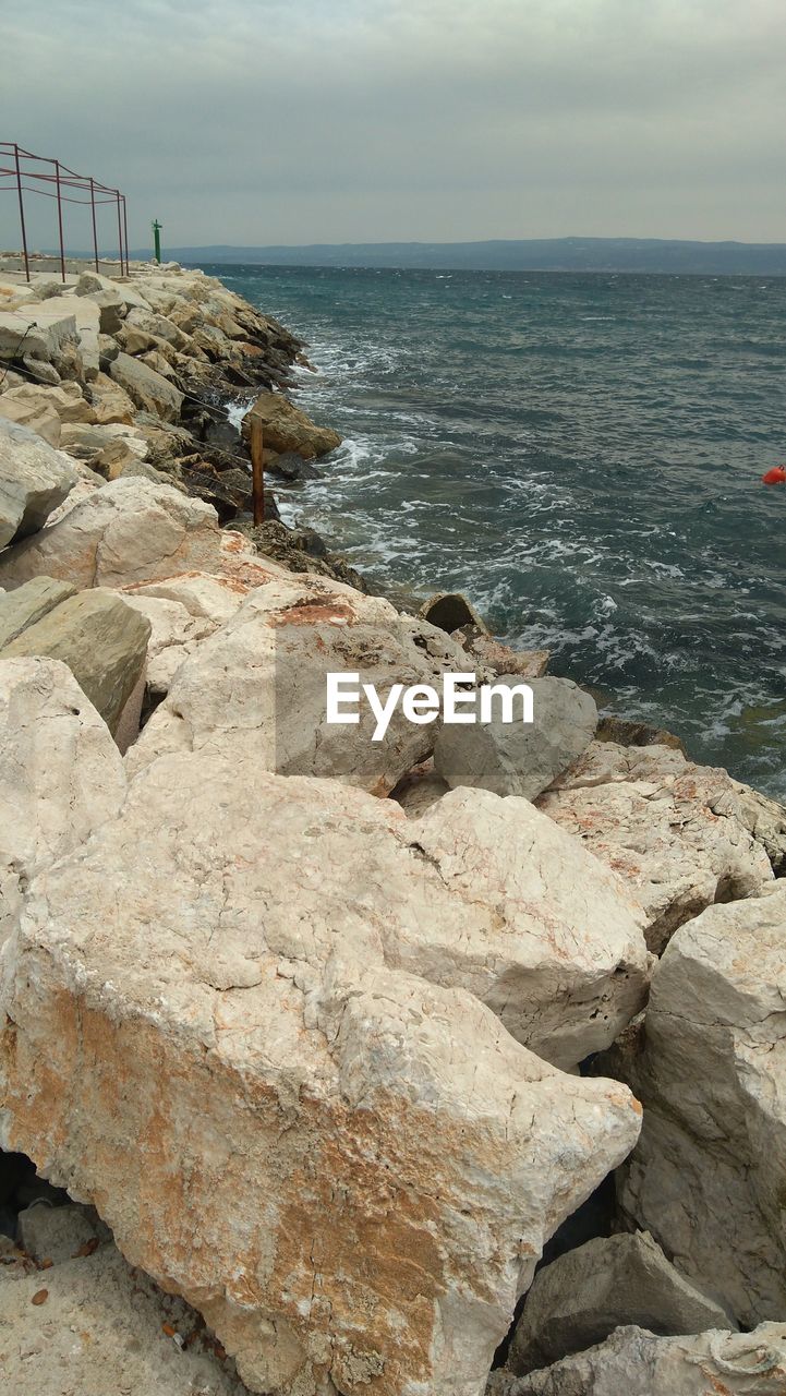 SCENIC VIEW OF ROCKS ON BEACH AGAINST SKY