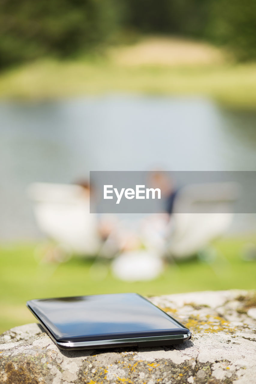 Laptop on rock with couple in background