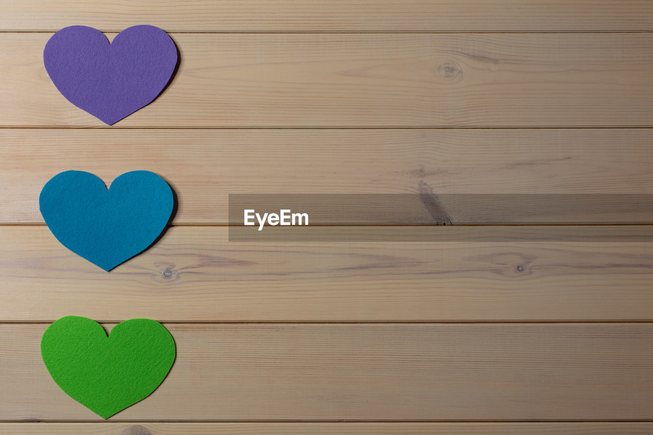 Valentines day beige wooden background with colorful felt hearts. copy space. mockup