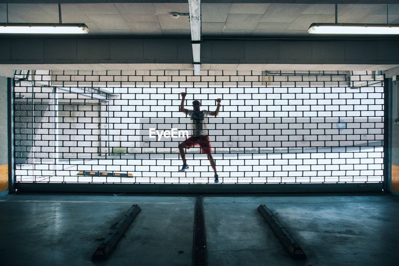 Man climbing on metal grate of window