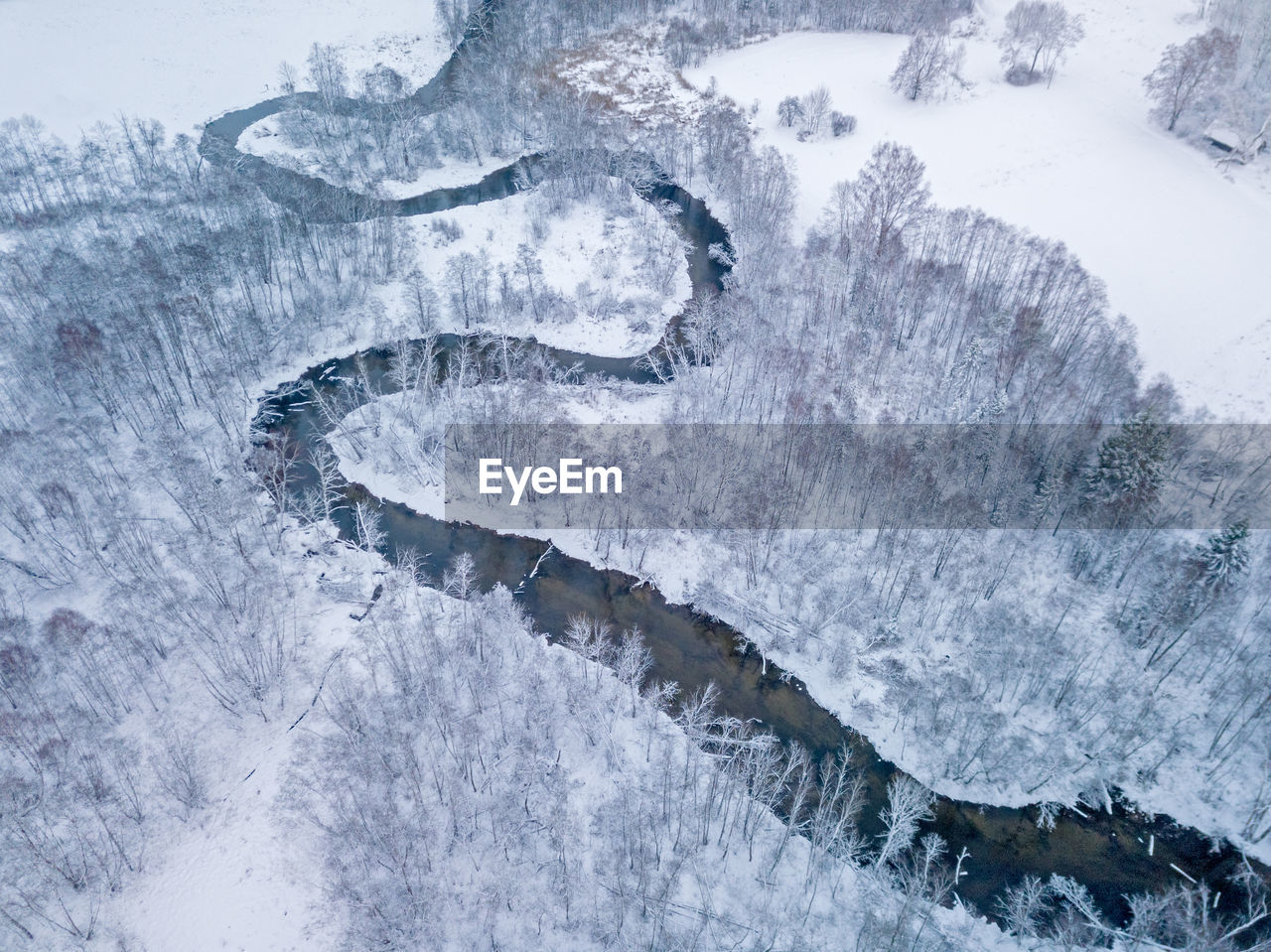 High angle view of stream amidst snowy land