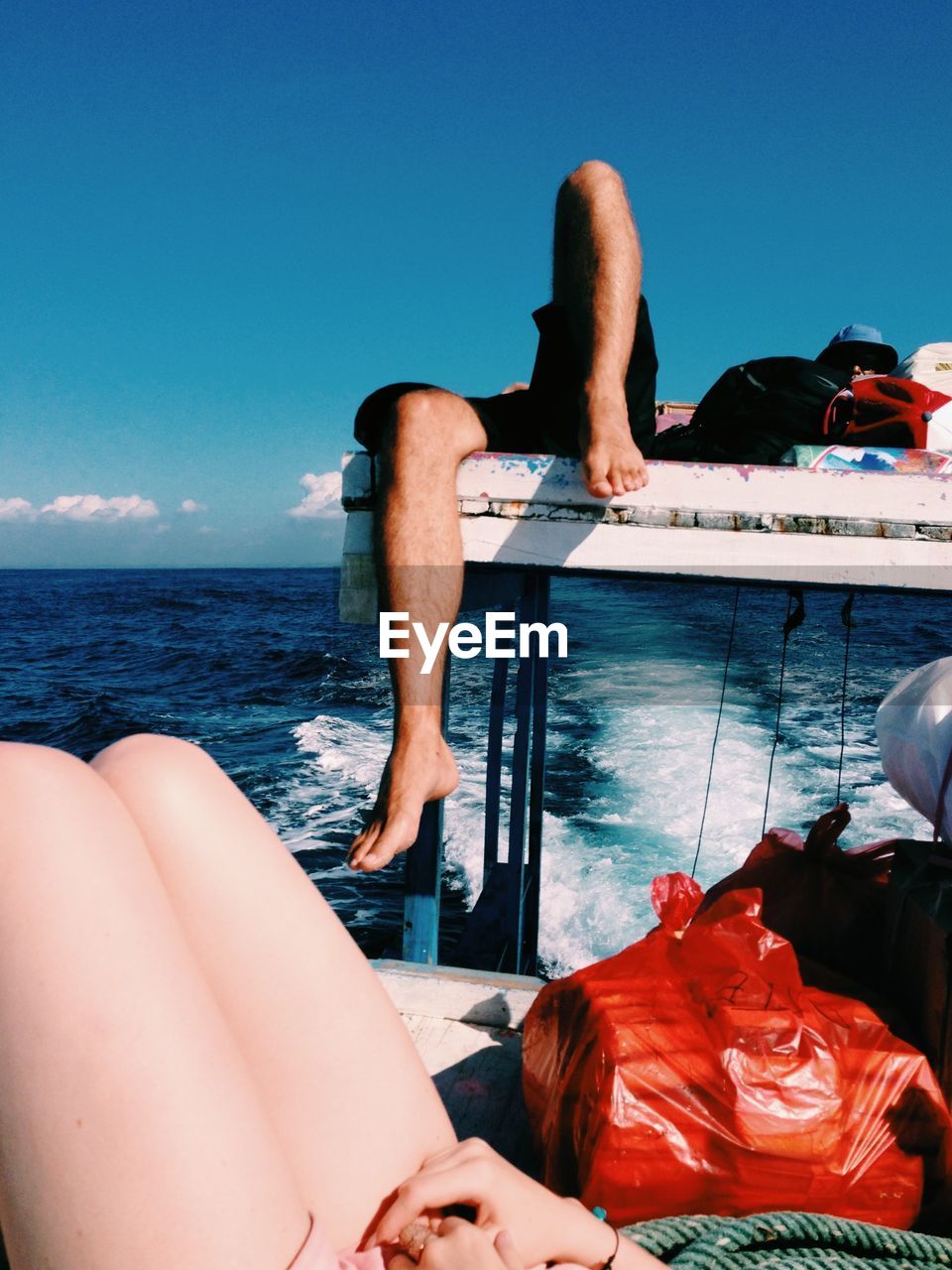 Two people lying on boat deck at calm blue sea