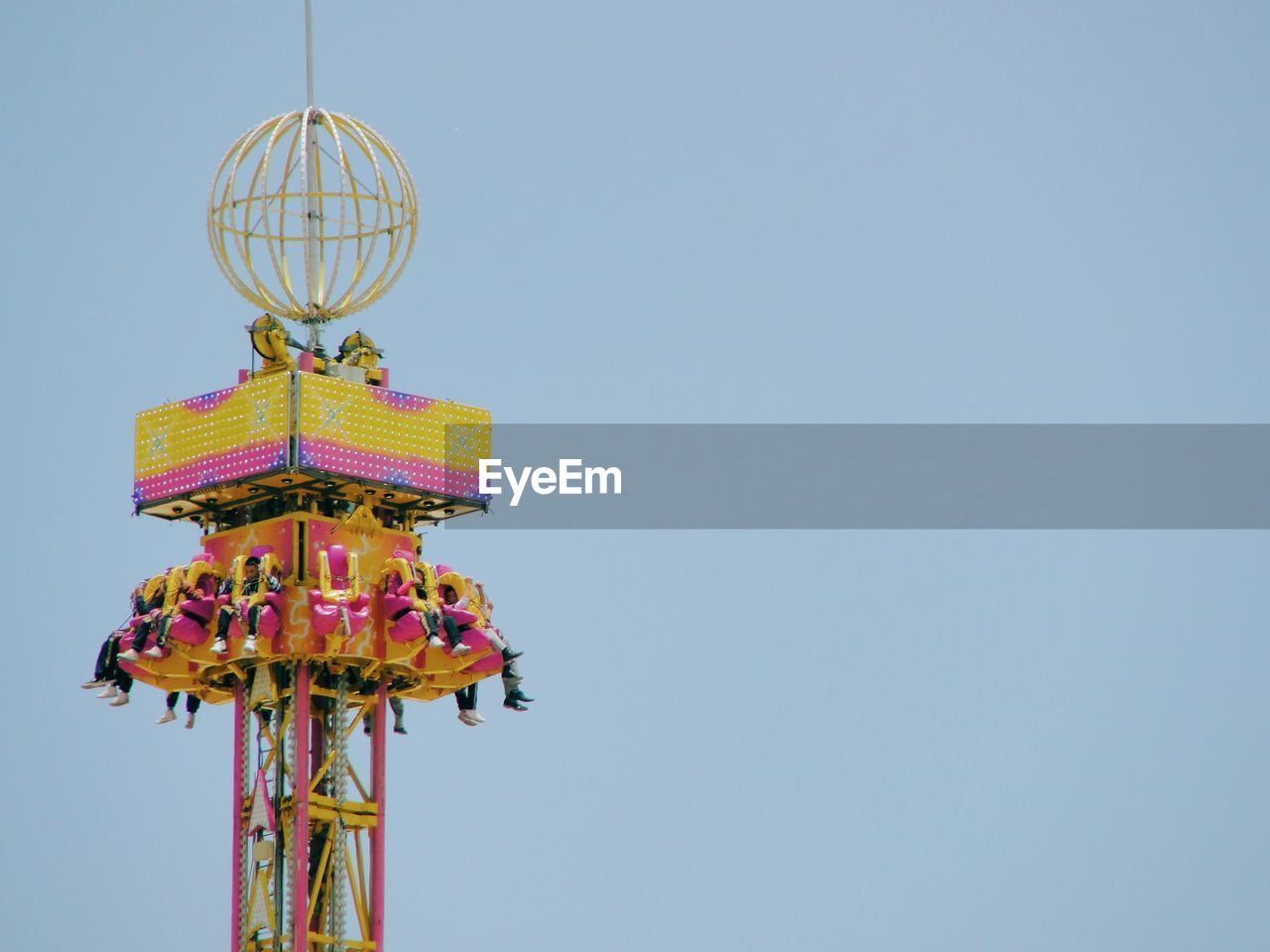 Low angle view of people enjoying free fall against clear sky