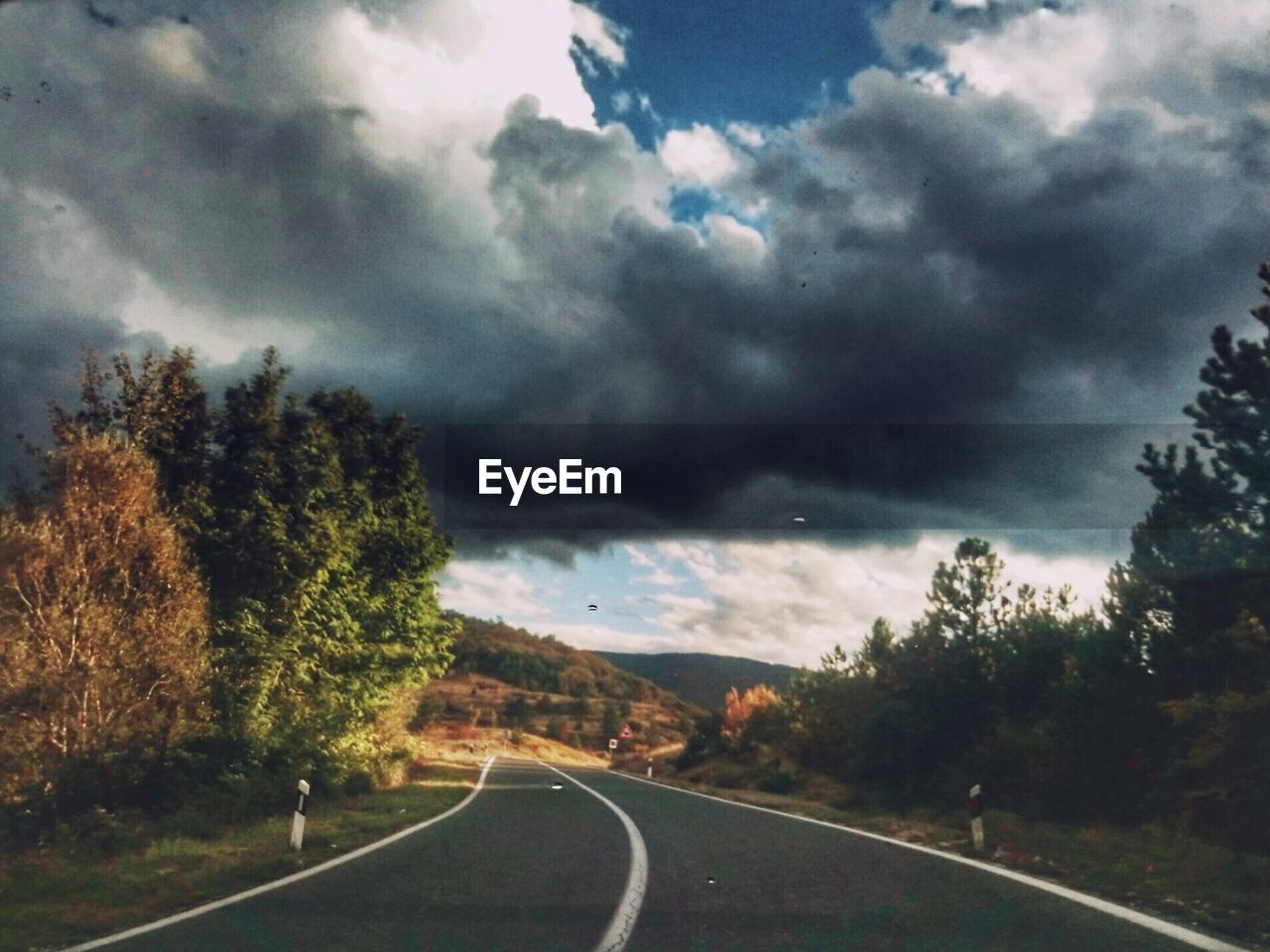 ROAD PASSING THROUGH FOREST AGAINST SKY