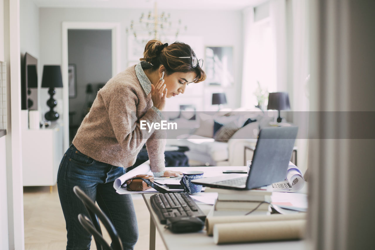 Woman standing by table working from home