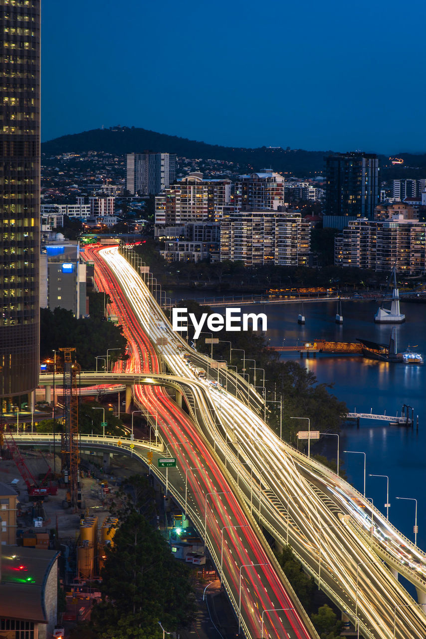 Aerial view of light trails on road by buildings