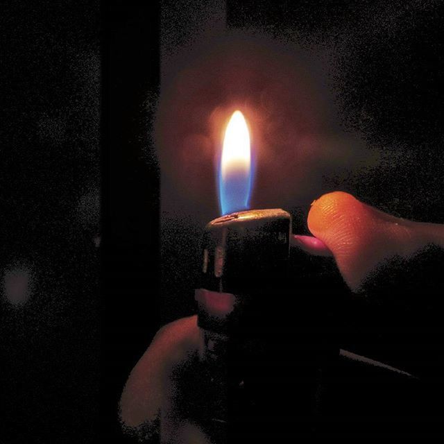 CLOSE-UP OF LIT CANDLES IN THE DARK