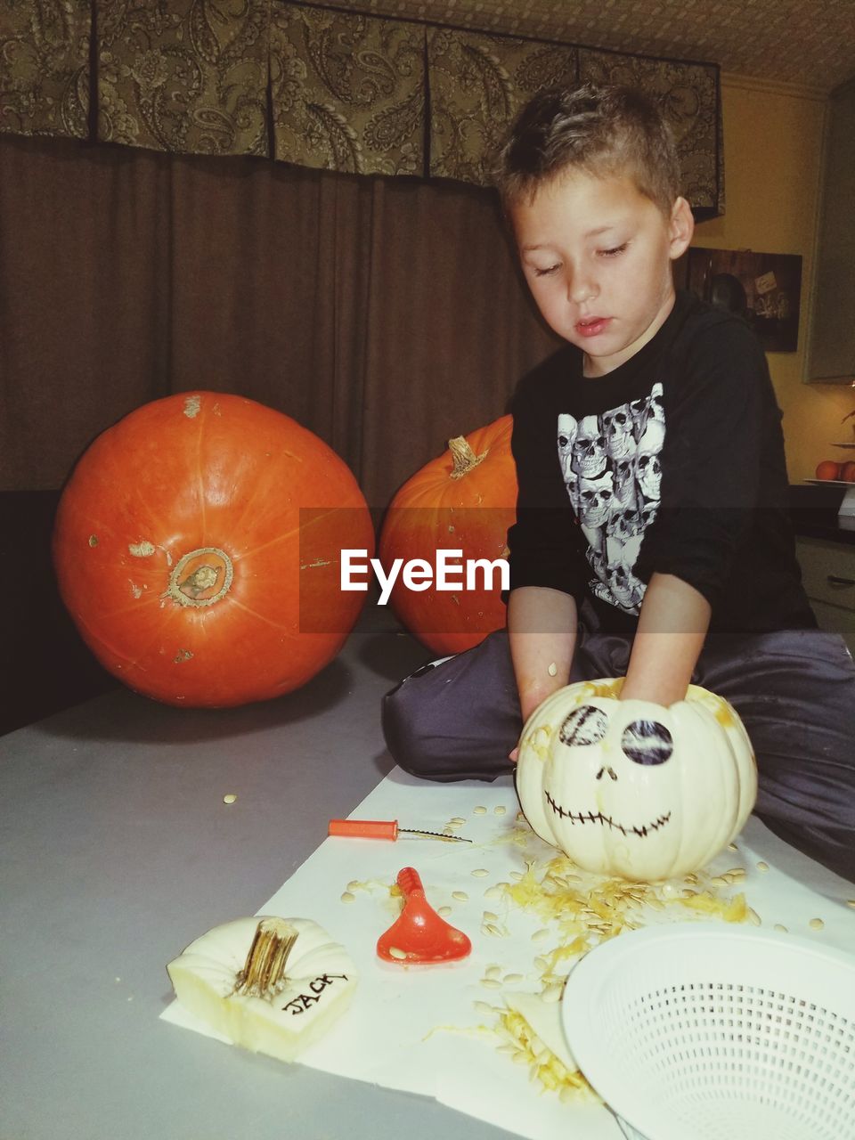 FULL LENGTH OF CUTE BOY WITH PUMPKIN AT HOME