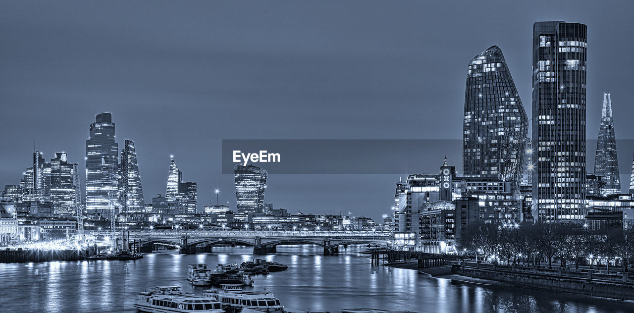 MODERN BUILDINGS BY RIVER AGAINST SKY IN CITY