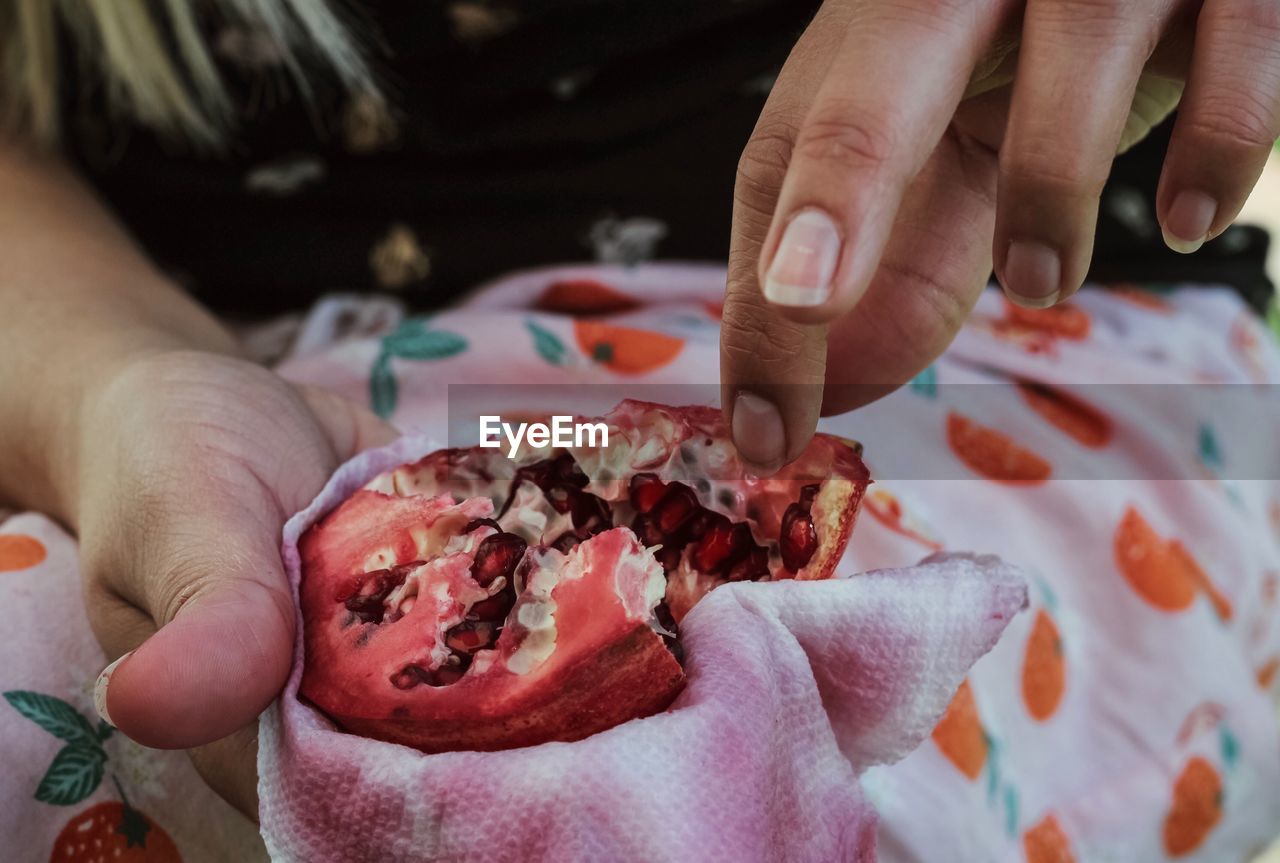 Midsection of person holding pomegranate 