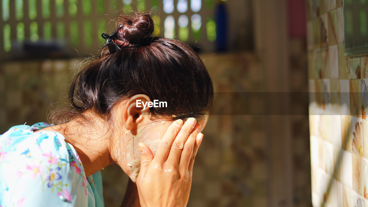 A beautiful woman is washing facial mask in bathroom after applying face mask.