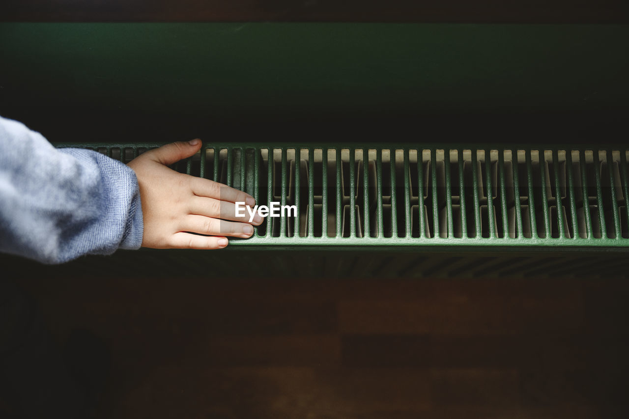 Hand of boy touching radiator at home