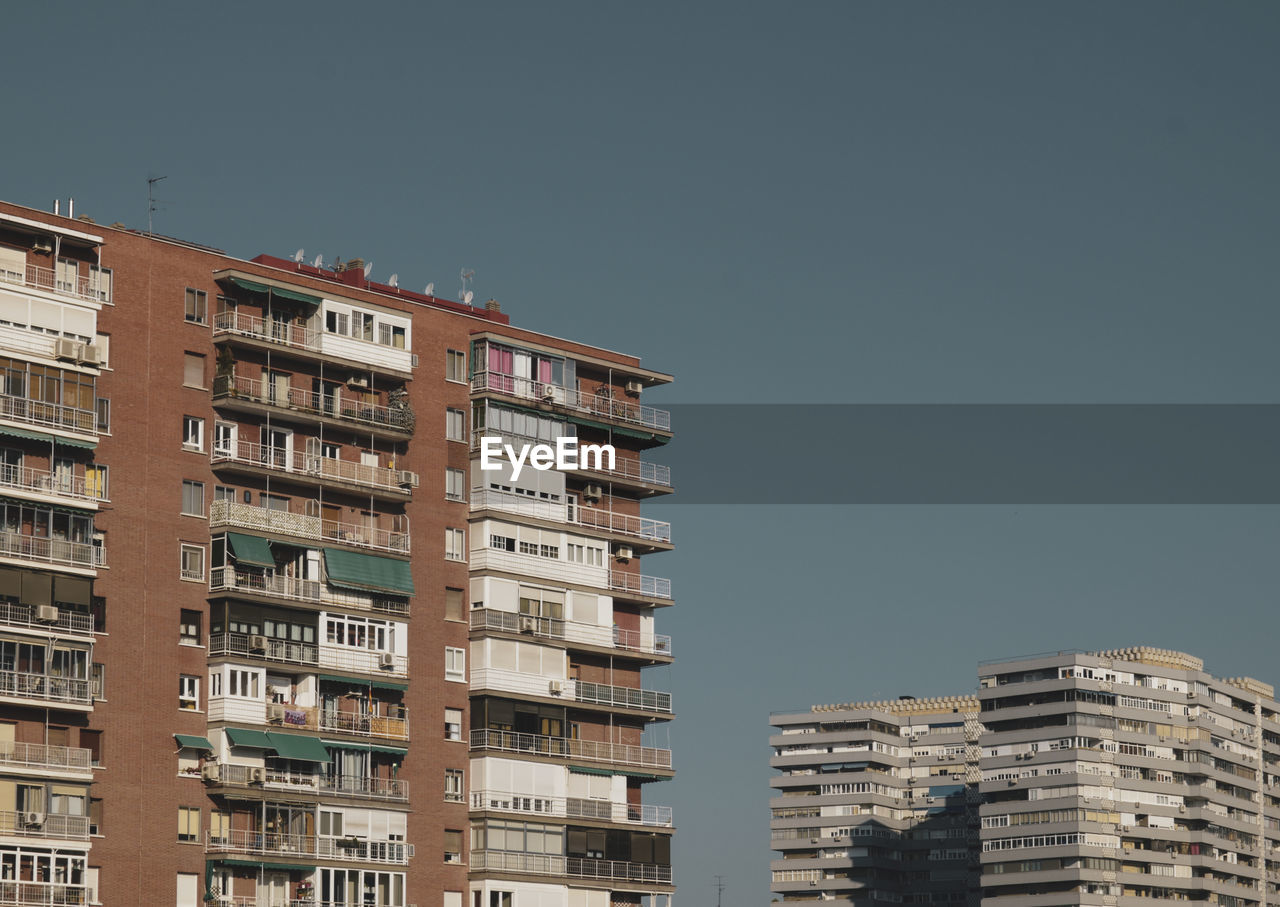 Low angle view of residential buildings in madrid, spain, against blue sky