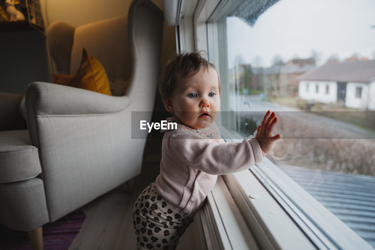 Baby girl standing in front of window