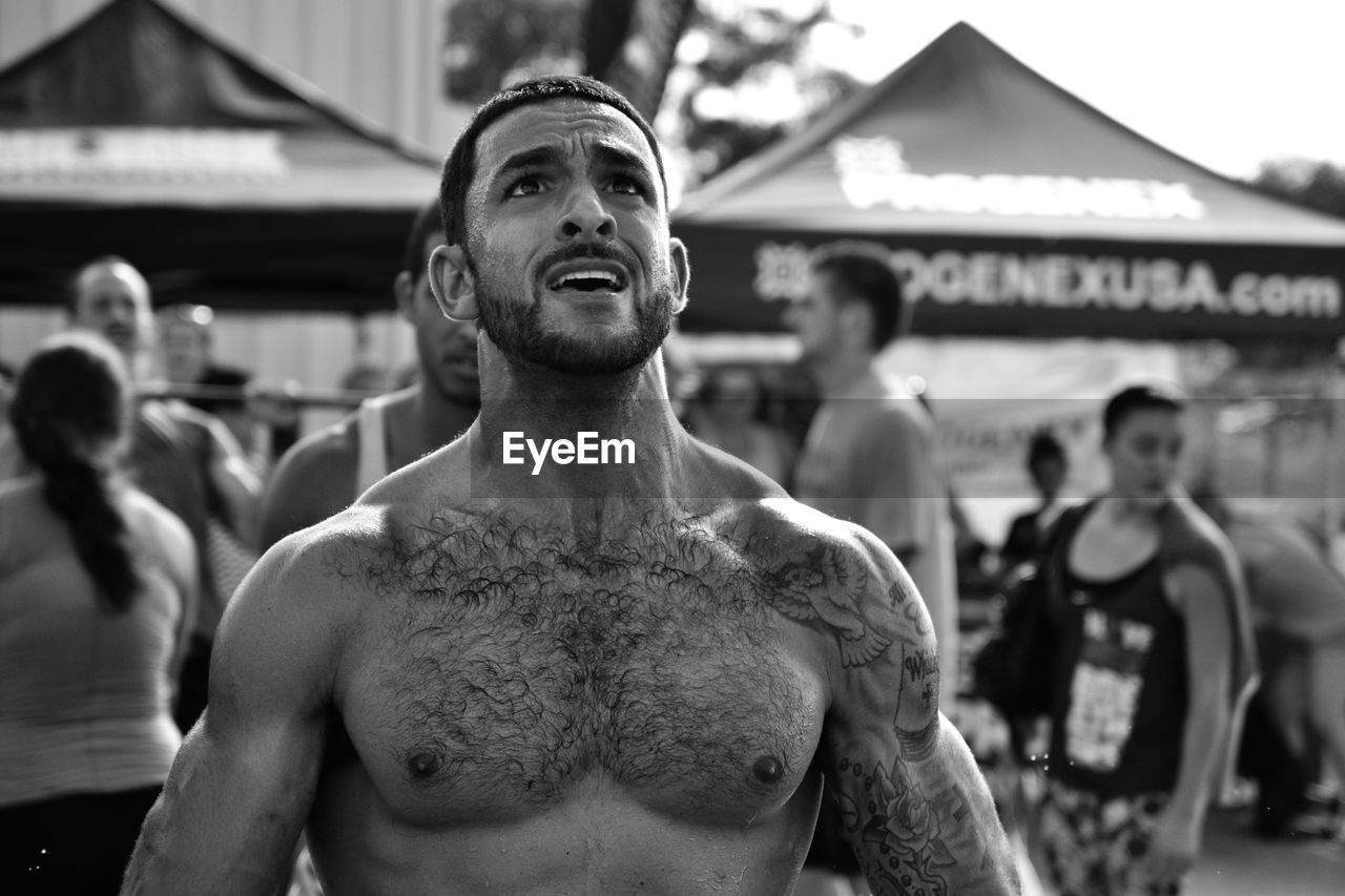 Worried shirtless man looking up at carnival