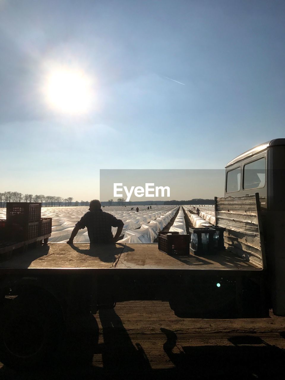 MAN SITTING ON SHORE AGAINST SKY