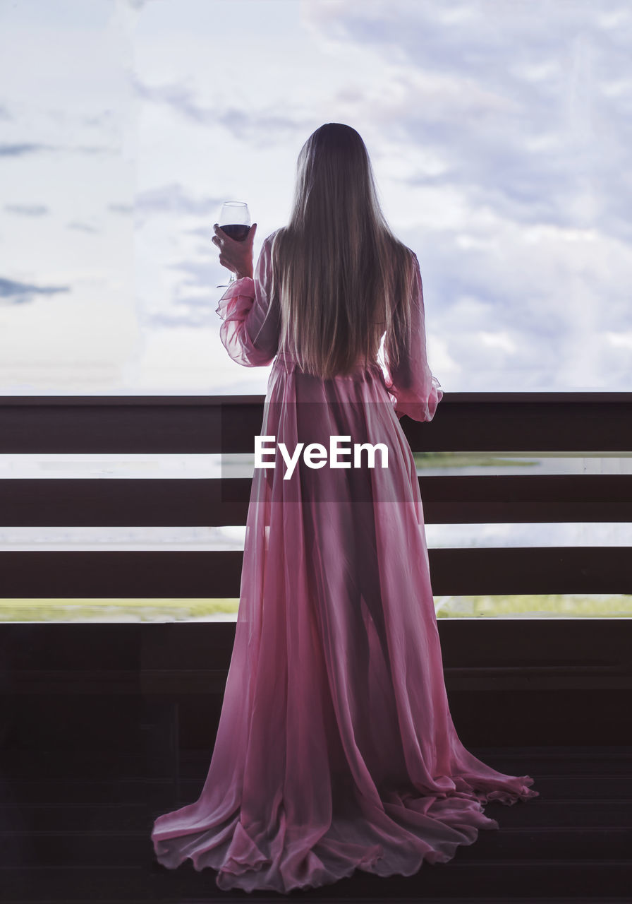 A beautiful girl with long white hair in a pink transparent negligee with a glass of red wine