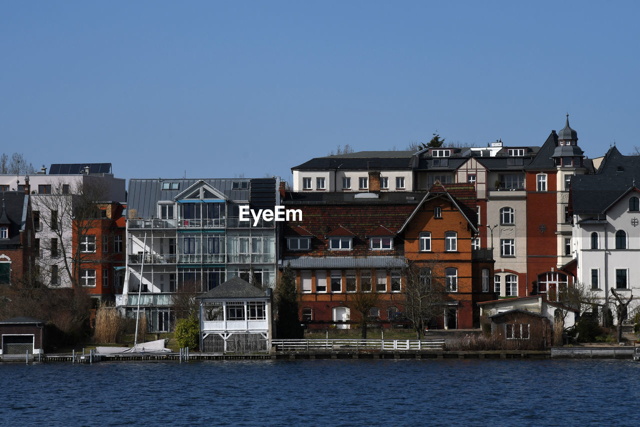 BUILDINGS BY RIVER AGAINST SKY