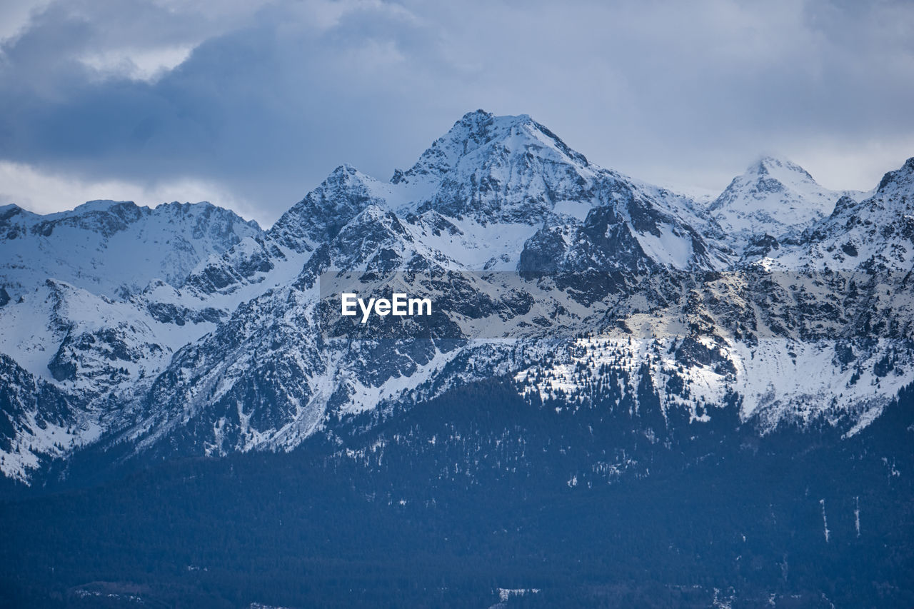 Scenic view of snowcapped mountains against moody sky