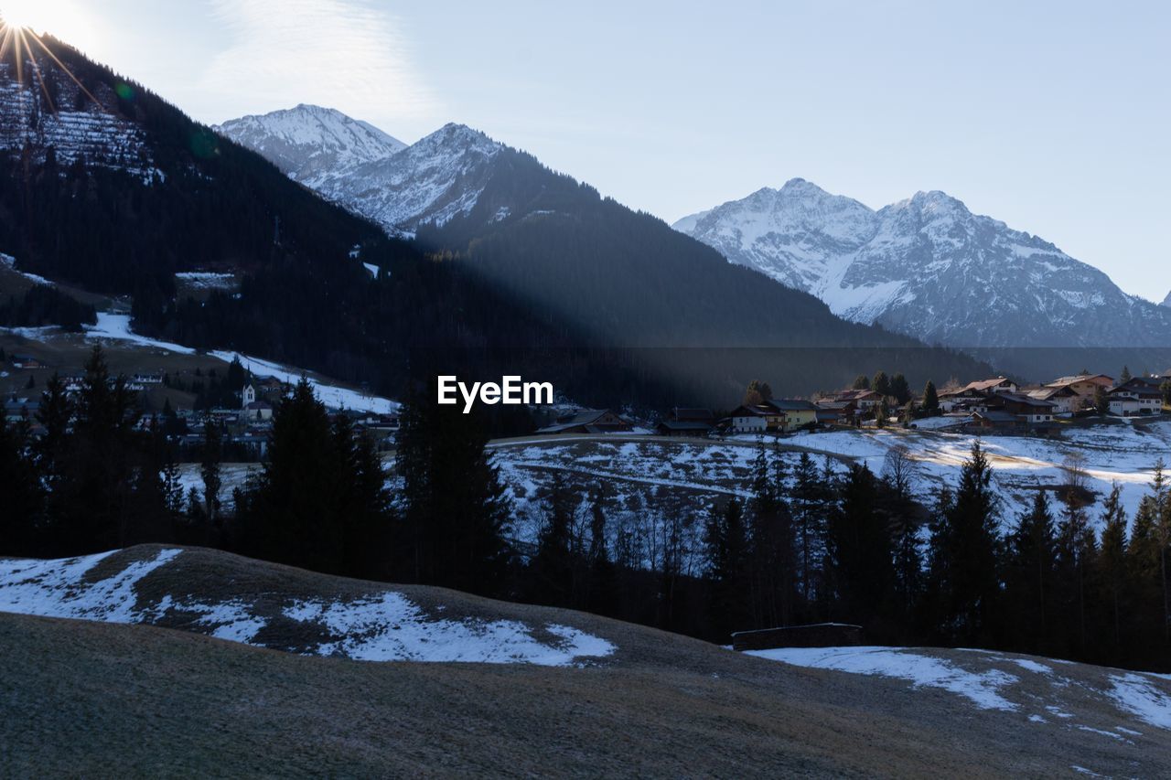 Scenic view of village with snowcapped mountains against sky