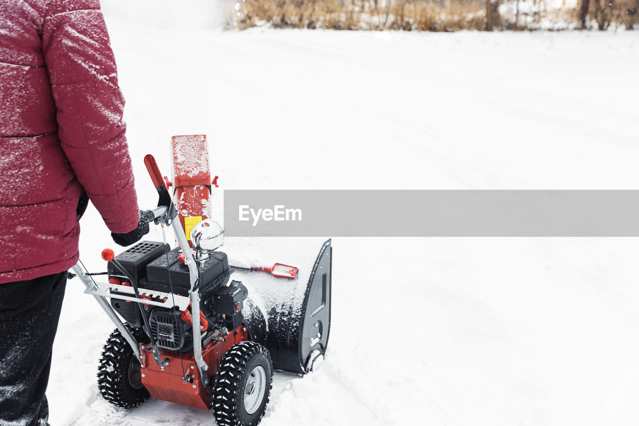 Detail of portable red snow blower powered by gasoline in action. man outdoor use snowblower machine
