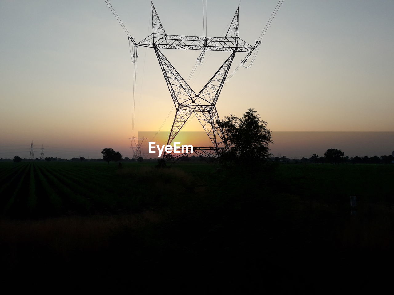 ELECTRICITY PYLON ON FIELD DURING SUNSET